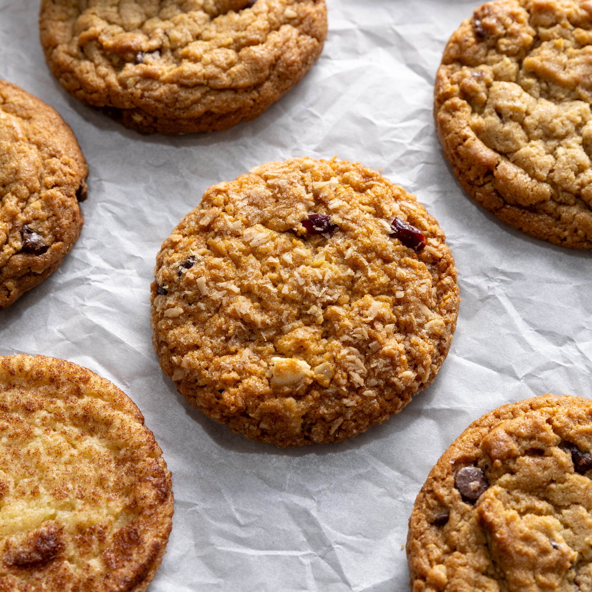Six freshly baked cookies on parchment paper, made from ready-to-bake frozen cookie dough