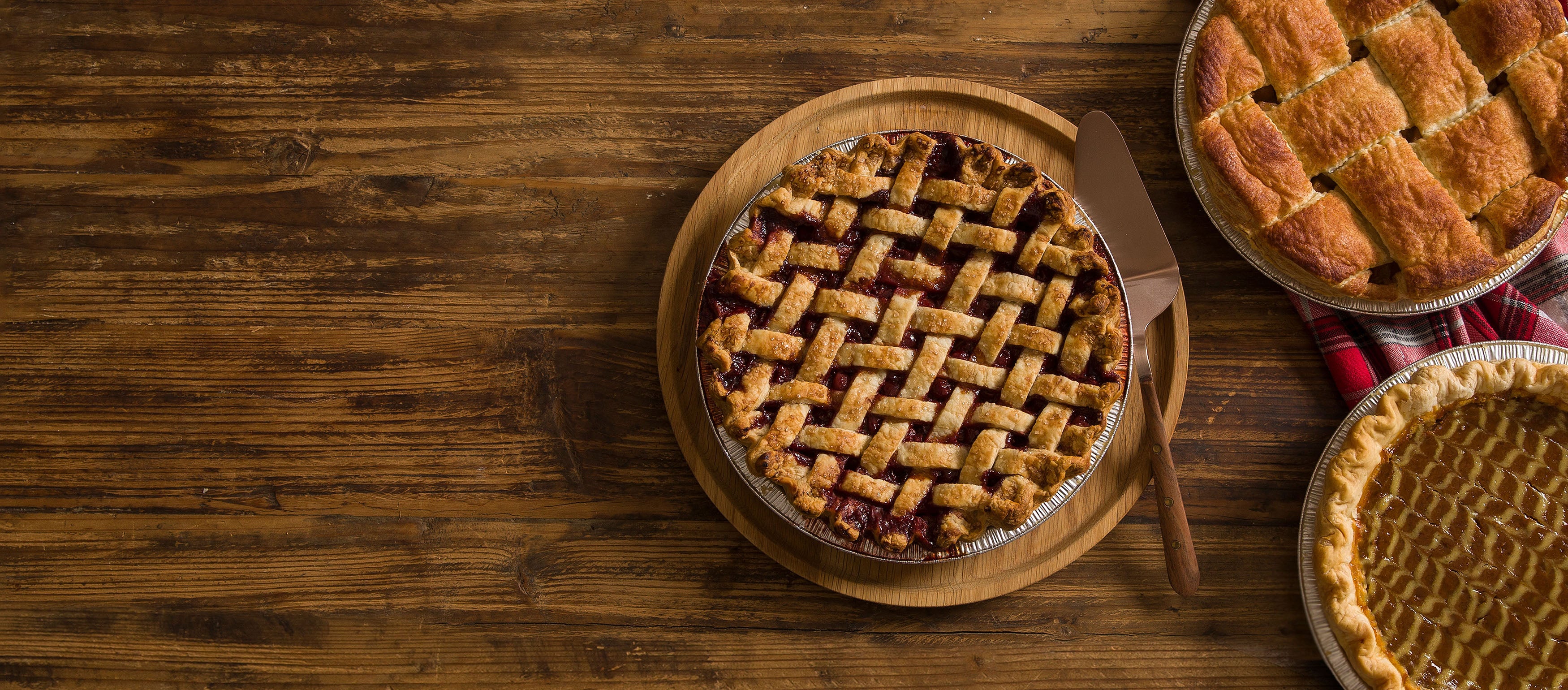 Wood tabletop with 1 spiced cherry pie, 1 apple pie and 1 pumpkin pie