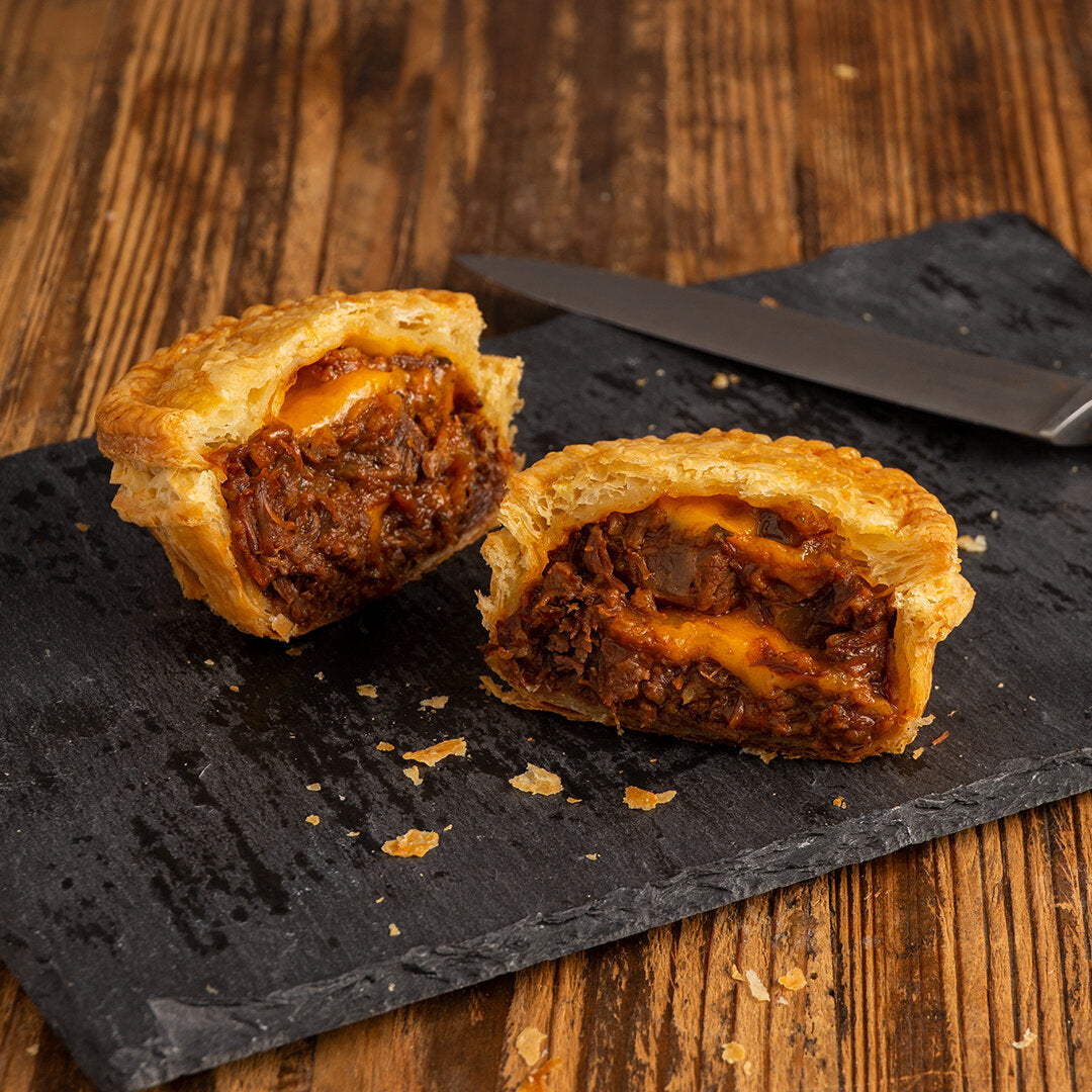 Bake-at-home beef pot pie cut in half, cross section showing puff pastry crust filled with tender steak and cheddar cheese