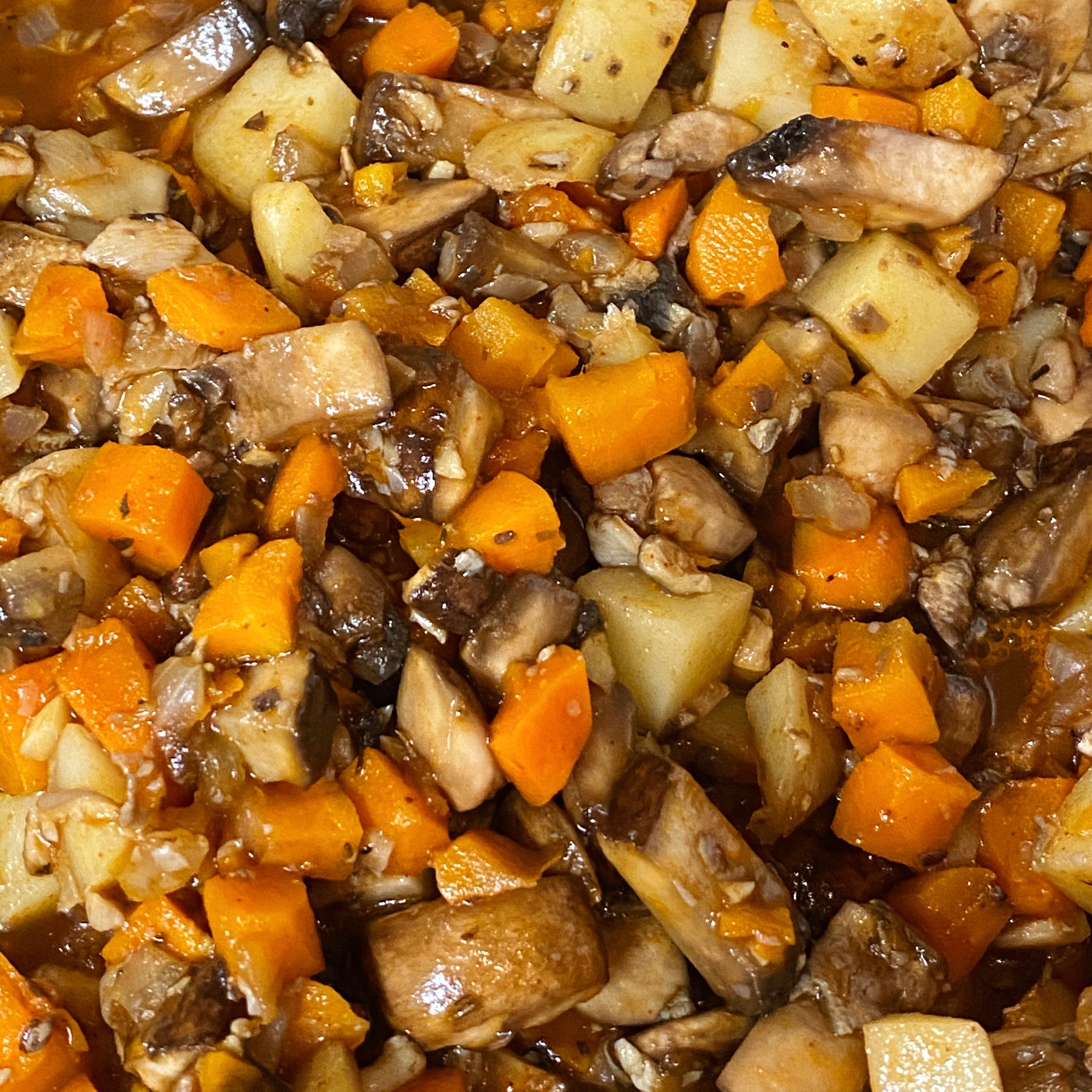 Close up of a bake-at-home vegan mushroom pot pie tomato, potato, carrot and onion